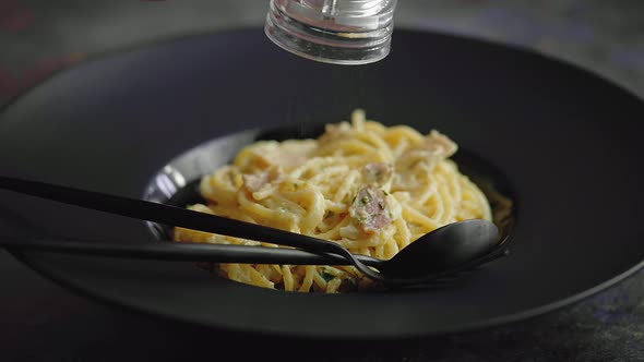 Slow Motion Video of Plate with Spaghetti Carbonara Being Sprinkled with Fresh Pepper