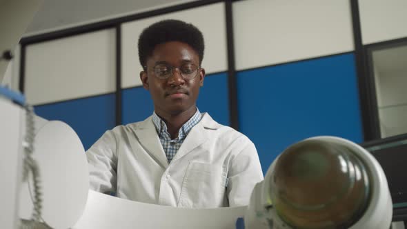 Bottom View of Young Confident African Doctor in White Uniform Working with