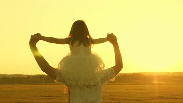 Concept of a Happy Childhood. Child Mom Play in the Meadow in the Sun. Mother and Little Daughter