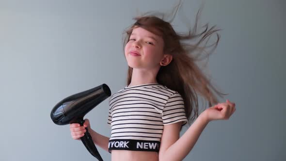 Little Girl Dries Her Hair with a Hair Dryer