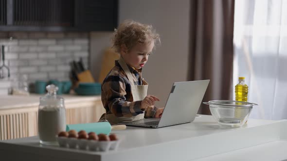 Toddler is Learning to Cook Watching Video for Children in Internet By Laptop Playing on Home