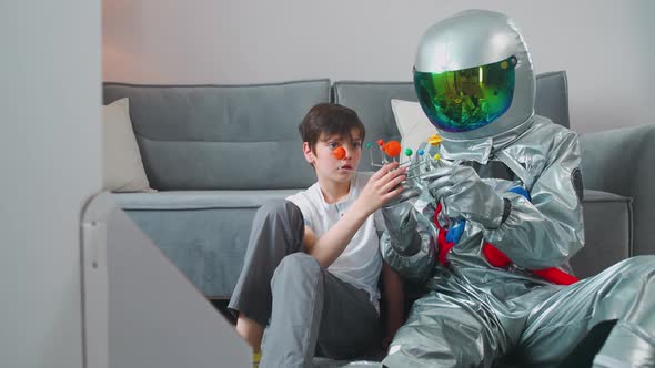 Father and Son Play in the Living Room at Home Father in an Astronaut Costume Sitting on the Floor