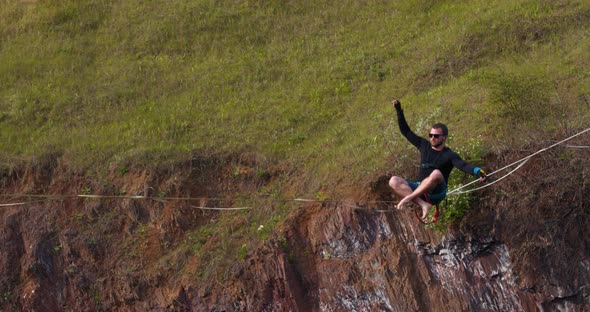 Slacklining a Man Is Sitting on a Rope Stretched Over a Massive Pit Balance