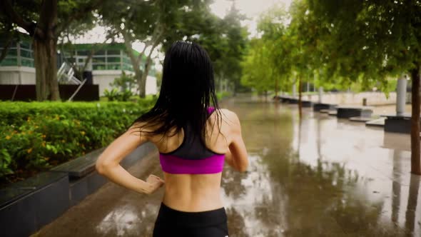 Middle-aged Asian woman jogging in the rain in Singapore 