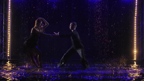 Young Beautiful Couple Dancing Sensual Bachata Dance. Silhouettes of Dancers Moving in Raindrops