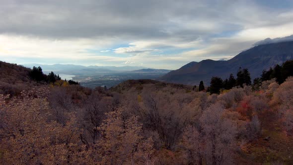 Looking at the distant town from high in the mountains during autumn - aerial pull back view