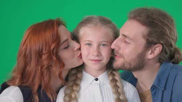 Portrait of Smiling Woman and Man Happily Kissing Female Child and Looking at Camera on Green Chrome