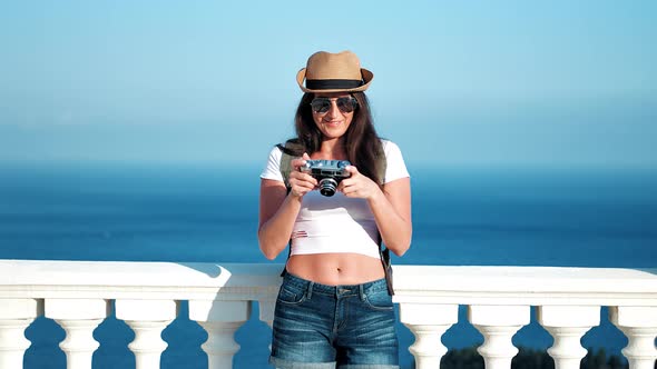 Woman Traveler in Hat and Sunglasses Taking Photo Using Vintage Camera Medium Long Shot