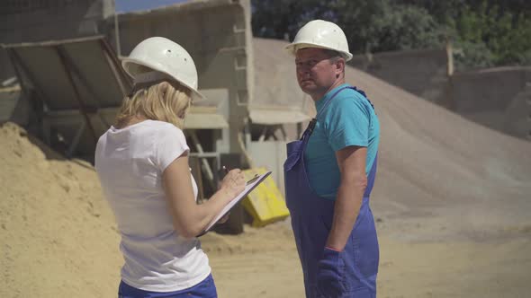 Middle Shot of Confident Caucasian Woman with Documents Talking To Adult Man Outdoors on Production