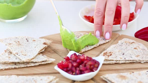 Preparing vegetarian toasts with avocado sauce and pomegranate seeds