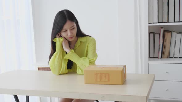 Young asian woman walking and holding cardboard box at home.