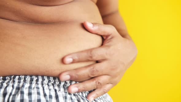 Fat Man with a Big Belly Against Yellow Background