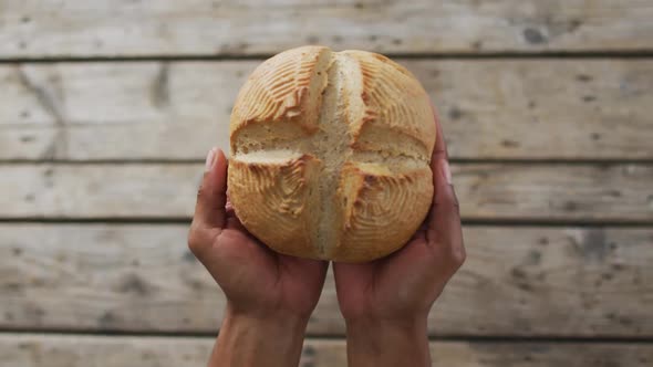 Video of bread in hands on wooden worktop seeing from above