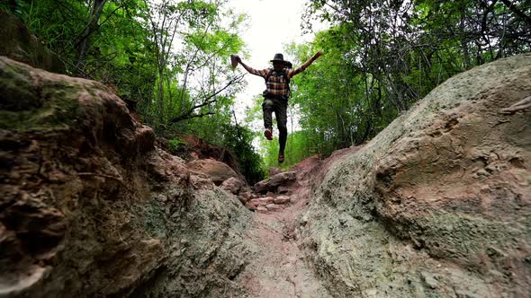 slow-motion of man traveler with backpack running and jumping in the natural forest