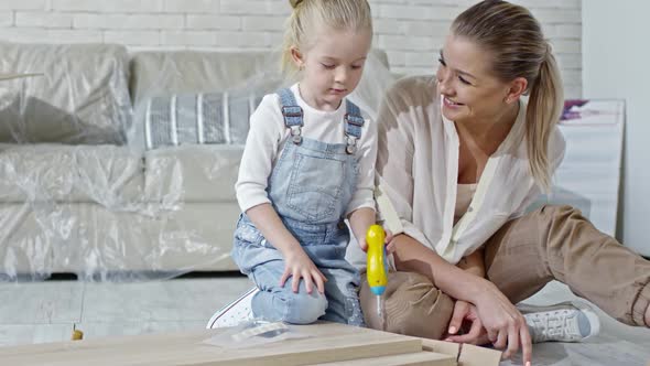 Girl Assembling Furniture with Toy Screwdriver