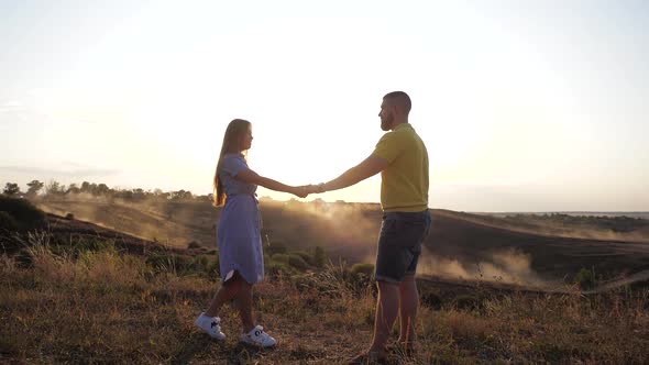 Guy Holds His Lover's Hand and Twists It To Himself. Young Beautiful Couple of People in Love Spend