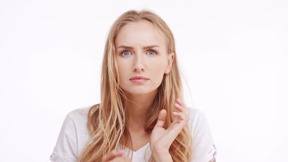 Young Beautiful Caucasian Blonde Girl Trying to Find Pimple on Forehead on White Background