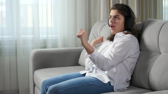 Disabled Woman in Headphone Listens to Music Dancing on Sofa