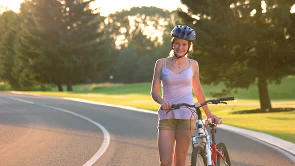 Young Woman with Bicycle Walking on Road