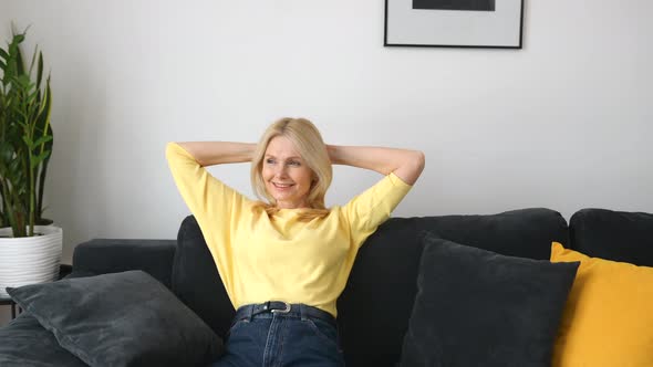 Serene Carefree Middleaged Woman with Long Hair Sitting on the Sofa