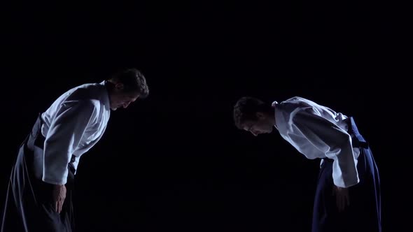 Two Masters Martial Arts Aikido Bow To Each Other. Shot Isolated on Black Background. Slow Motion