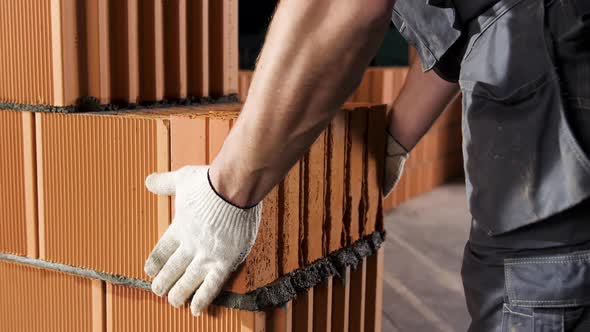 Man putting heavy brick on mortar