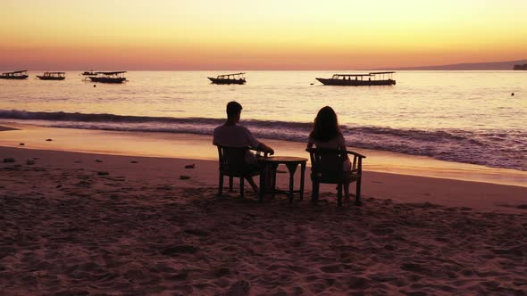 Two lovers sunbathe on marine coastline beach trip by blue sea with white sandy background of Bali n