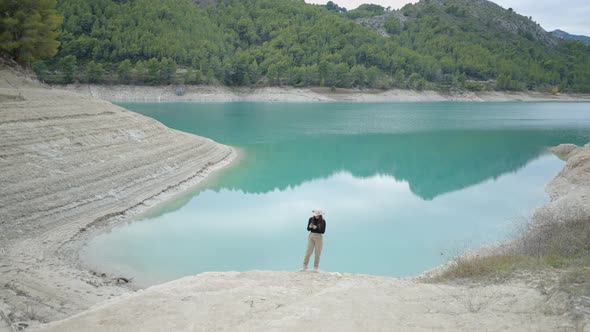 Wide View of Girl Putting Phone in Pocket and Walking By Lake in Spain