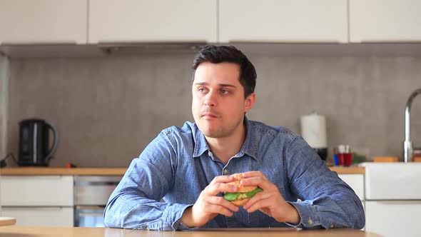 man eating burger on a table in kitchen in home