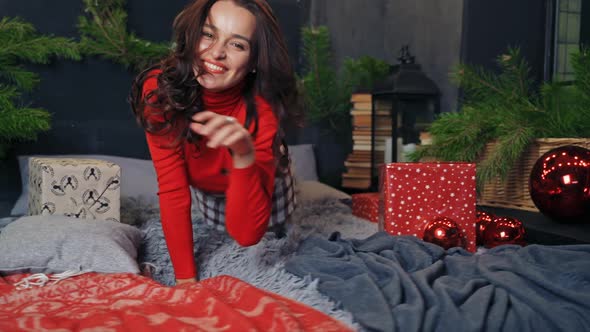 Happy girl enjoys Christmas at home. Young woman on bed resting during New Year. 