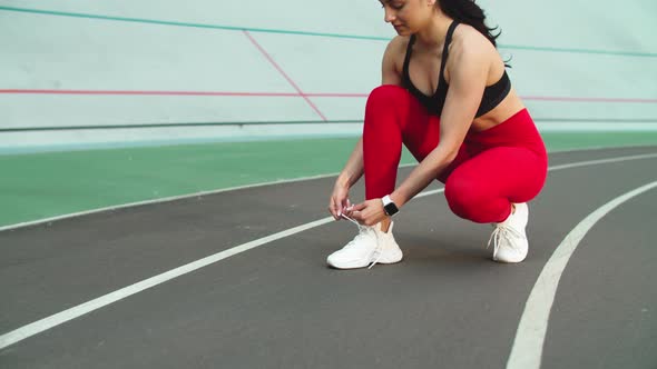 Sport Woman Lacing Up Sneakers for Workout on Track. Woman Runner Tying Up Shoes