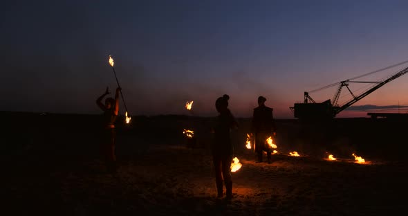 Fire Show Three Women in Their Hands Twist Burning Spears and Fans in the Sand with a Man with Two