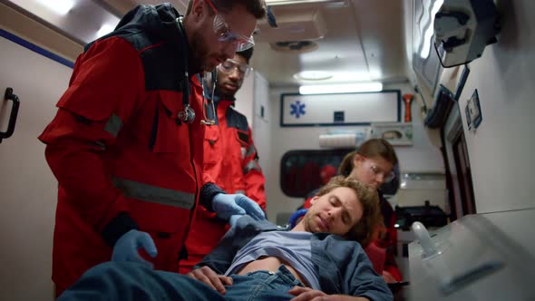 Emergency Care Assistant Providing Medical Help to Patient in Ambulance Car