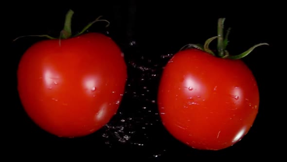 Closeup of the Two Ripe Red Tomatoes Colliding on the Black Background
