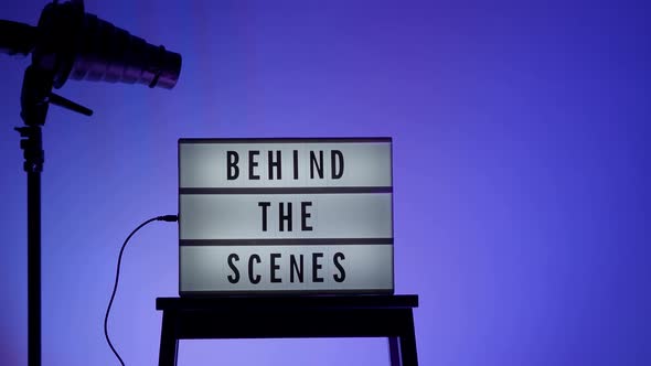 Behind the scene letters on cinema light box. Black text on white LED lightbox of word Behind the
