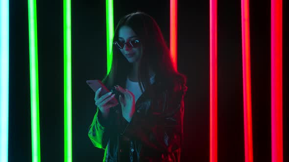 Portrait of a Pretty Young Beautiful Woman in Stylish Sunglasses Is Texting on Her Smartphone. Slow