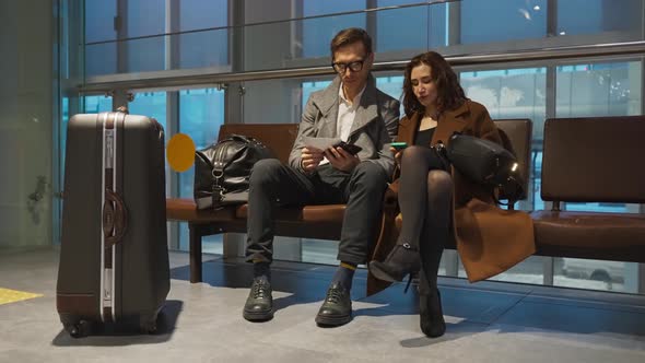 Young Couple is Waiting for a Transfer at the Airport with Passports and Suitcase