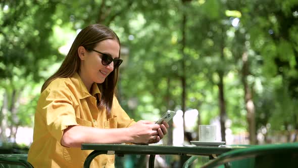 Side View at Smiling Young Woman Using Smartphone Outdoors Texting Online alt