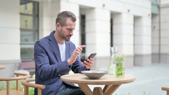 Upset Man Reacting to Loss on Smartphone Side Pose