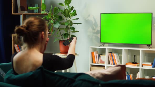 Woman Watching TV with Green Screen in Living Room Back View