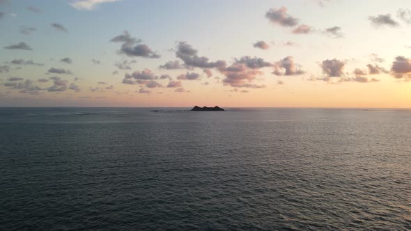 Drone, Moving In Towards Island, Surrounded by Sea, at Sunset with Small Clouds