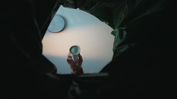 A Hand Over a Basket Throws a Can Into the Basket