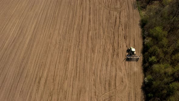 Aerial view large tractor cultivating a dry field. Top down aerial view tractor cultivating ground 