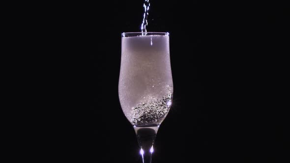 Champagne Being Poured Into a Flute Glass on Black. Slow Motion. End Process