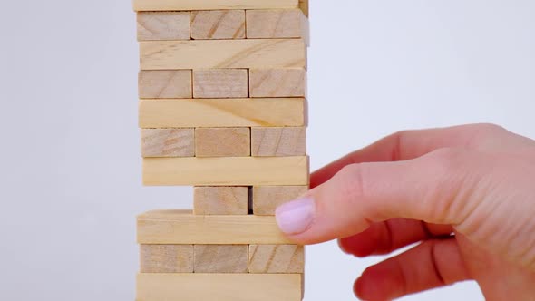 Female Hand Playing Wooden Block Removal Tower Game at Home