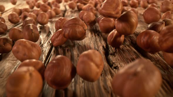 Super Slow Motion Detail Shot of Hazelnuts Rolling Towards on Wooden Background at 1000Fps