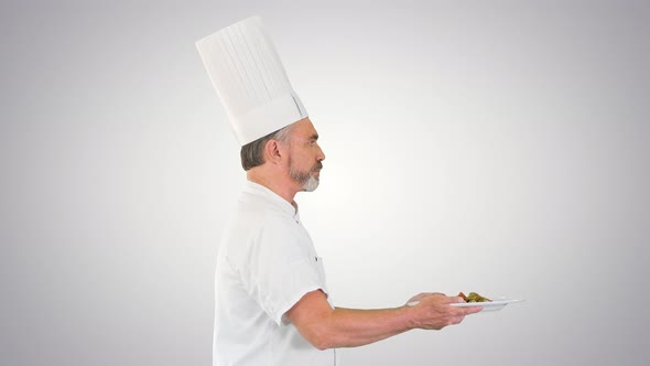 Male Chef White Uniform Running with a Plate of Salad on Gradient Background