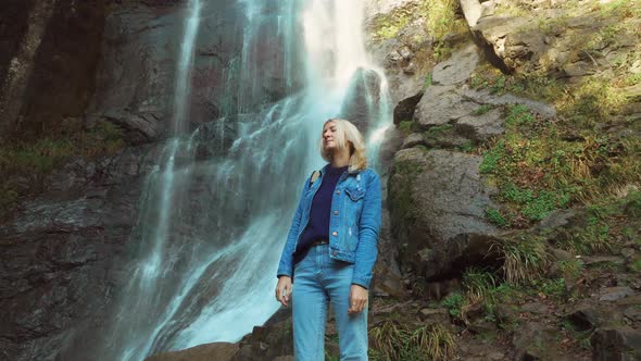 A young traveler smiled at the camera and enjoyed the wildlife with a waterfall