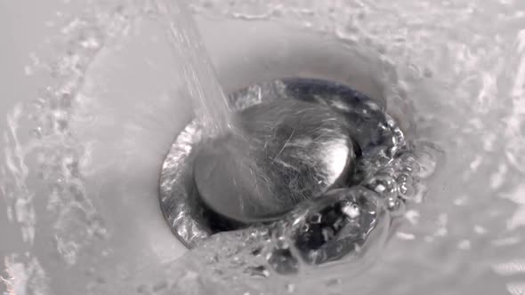 Water Flowing Down the Drain. Drain the Water in the Sink. Slow Motion Shot