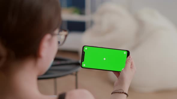 Closeup of Young Woman Holding Horizontal Smartphone with Green Screen Watching Influencer Vlog